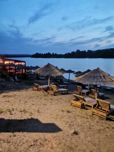 a group of chairs and umbrellas on a beach at Apartman Janković in Veliko Gradište