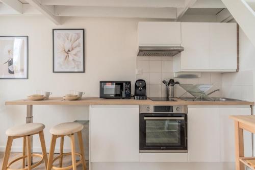 une cuisine avec des armoires blanches et un comptoir avec des tabourets dans l'établissement Functional & equipped duplex studio, Old Lille, à Lille