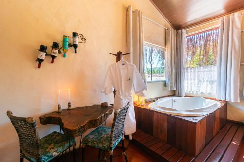 a bathroom with a bath tub and a table and chairs at Pousada Do Lado de Lá in Pirenópolis