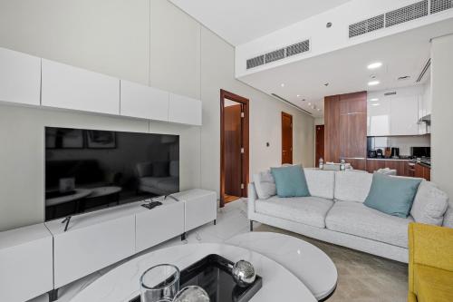 a white living room with a couch and a tv at Unlock J One Downtown Dubai in Dubai