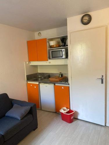 - une cuisine avec des armoires orange et un canapé dans la chambre dans l'établissement Studio Residence Tourmalet-La Mongie, à Bagnères-de-Bigorre