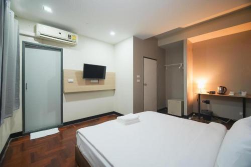 Un dormitorio con una cama blanca y un televisor. en GO INN BTS ST Louis Silom - โกอินน์ บีทีเอส เซนต์หลุยส์ สีลม 4, en Yan Nawa