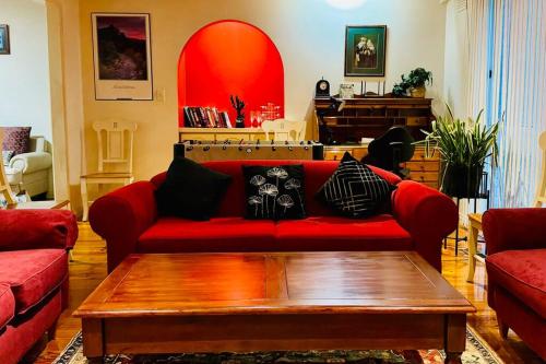 a living room with a red couch and a coffee table at Cosy Vintage Home in Craigieburn