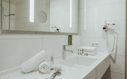 a white bathroom with a sink and a mirror at Appartements Amarella in Bad Hofgastein