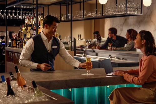 a man and a woman standing at a bar with a drink at Crowne Plaza Utrecht - Central Station by IHG in Utrecht