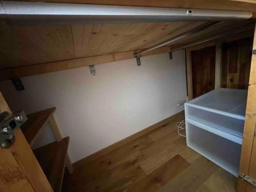 Cette chambre mansardée est dotée d'un mur blanc et de parquet. dans l'établissement Studio fonctionnel neuf, à Paris