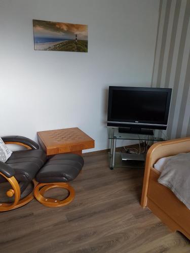 a living room with a tv and a couch and a table at Ferienhaus Leuchtturm in Geestland