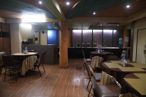 a dining room with tables and chairs and a bar at Hill Forest Resort in Lonavala