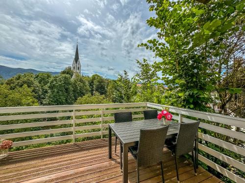 a table and chairs on a wooden deck with a church at Apartmaji Vogelnik in Radovljica