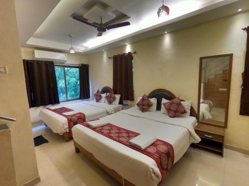 a hotel room with two beds and a mirror at Hill Forest Resort in Lonavala