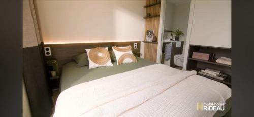 une chambre avec un grand lit blanc avec deux oreillers dans l'établissement Mobilhome neuf Domaine 4 étoiles Ile d'Or terrasse et jacuzzi privé vue mer exceptionnelle, à Saint-Raphaël