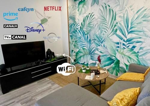 un salon avec une télévision et une fresque murale représentant des feuilles dans l'établissement Le Jungle - Parking et wifi gratuit - Balcon - Alexa, à Saint-Alban