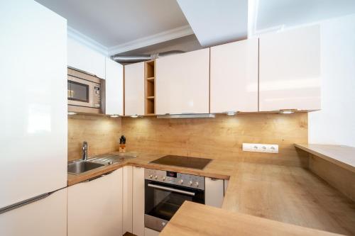 a kitchen with white cabinets and a sink at Familotel Kindl in Neustift im Stubaital