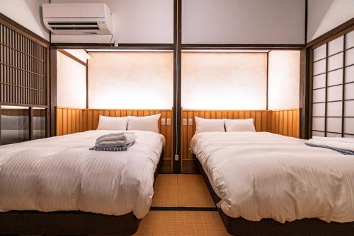 two beds in a room with windows at NIPPONIA Sado 佐渡相川 金山町 in Sado
