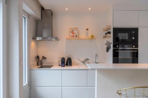 une cuisine avec des armoires blanches et un appareil noir dans l'établissement Attractive one-bedroom flat in the city centre, à Lille