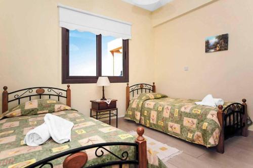 una camera d'albergo con due letti e una finestra di Villa Melody Latchi a Neo Chorio