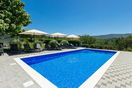 a swimming pool with chairs and umbrellas in a villa at Villa Matko - family destination in Zmijavci