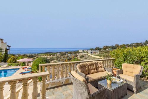 a balcony with two chairs and a table and a pool at Cliffside Villa in Tala