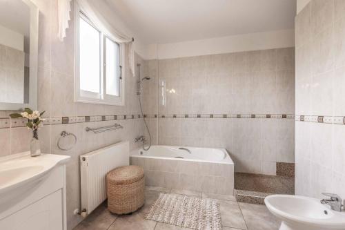 a white bathroom with a tub and a sink at Cliffside Villa in Tala