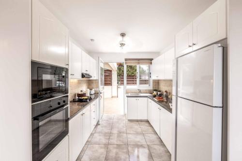 a white kitchen with white cabinets and appliances at Cliffside Villa in Tala