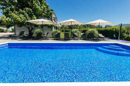 a blue swimming pool with chairs and umbrellas at Villa Matko - family destination in Zmijavci