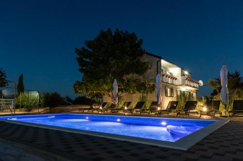 a swimming pool in front of a house at night at Villa Matko - family destination in Zmijavci