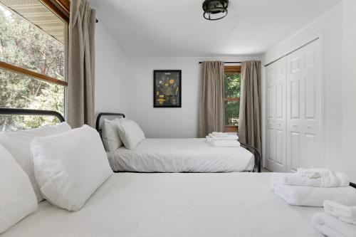 a white bedroom with two beds and a window at Torch Lake House Central Lake in Central Lake