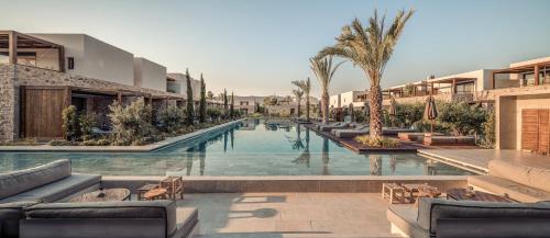 a pool at a resort with chairs and palm trees at Theros All Suite Hotel - Adults Only in Kos Town