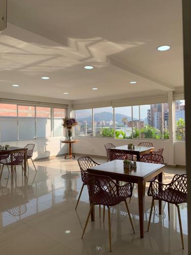 uma sala de jantar com mesas, cadeiras e janelas em Hotel Suite Comfort em Medellín