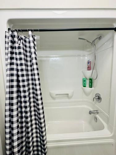 a bath tub with a black and white checkered shower curtain at Luxury Home 2 mins drive to Saugeen Shores beach in Port Elgin