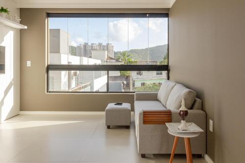 un salon avec un canapé et une grande fenêtre dans l'établissement Ap c/ Terraço, 2 quadras da Praia em Itapema P1771, à Itapema