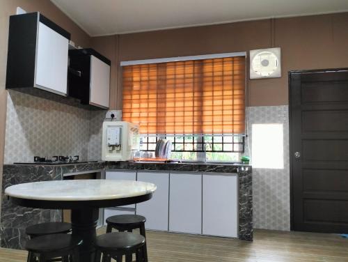 a kitchen with a table and chairs and a window at Nik Homestay in Tanah Merah