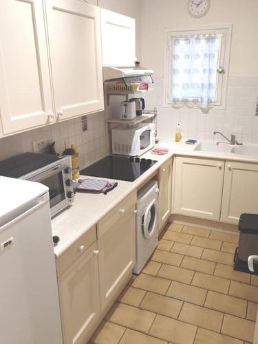 une cuisine avec des armoires blanches et un four à plaques de cuisson dans l'établissement T 1 avec terrasse face rivière à 1 min des thermes, à Gréoux-les-Bains