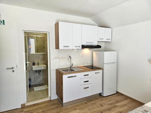 a kitchen with white cabinets and a sink at Holiday Resort Balota in Viganj