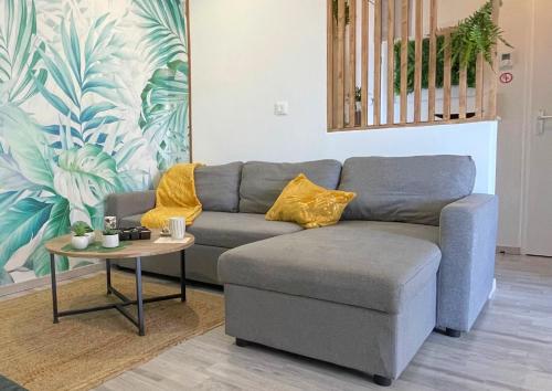 un salon avec un canapé et une table dans l'établissement Le Jungle - Parking et wifi gratuit - Balcon - Alexa, à Saint-Alban