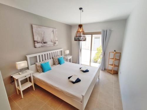 ein Schlafzimmer mit einem großen weißen Bett mit blauen Kissen in der Unterkunft Serena Luxury House in Caleta de Fuste