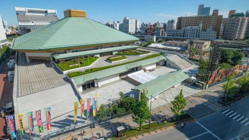 a large building with a green roof in a city at SKY BLUE HOUSE Asakusabashi in Tokyo