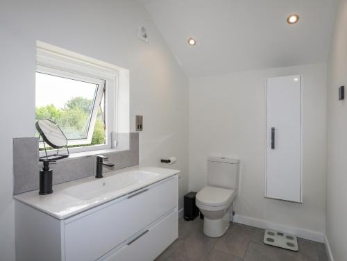 a white bathroom with a sink and a toilet at Swn Y Mor in Benllech