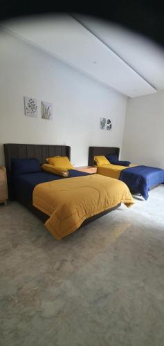 a bedroom with two beds with yellow and blue pillows at RaYa GuestHouse & Pool in Purwokerto