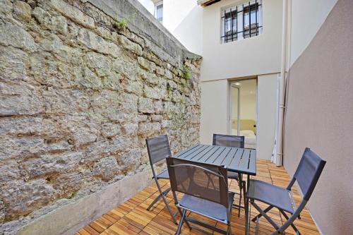 une table et des chaises sur une terrasse avec un mur en briques dans l'établissement Modern apt with Terrace - 2BR-4P - near Paris, à Aubervilliers