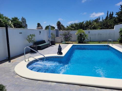 a swimming pool in a backyard with a white fence at La Casita in Chiclana de la Frontera