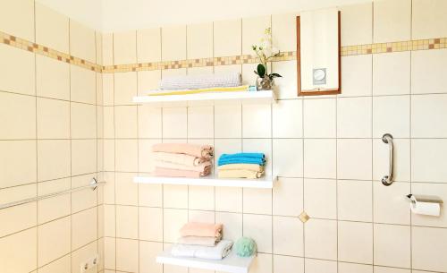 ein Badezimmer mit weiß gefliesten Wänden und Regalen mit Handtüchern in der Unterkunft Das Talhaus in Süsel