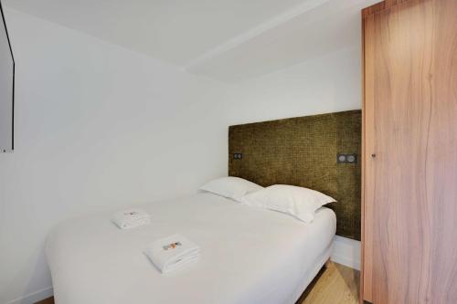 un lit avec des draps blancs et des oreillers dans une chambre dans l'établissement Pleasant and bright apt - 1BD-2P - near Paris, à Aubervilliers