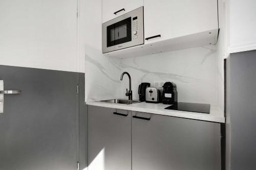une cuisine blanche avec un évier et un micro-ondes dans l'établissement Cosy Studio for 2P with A-C - Near Montmartre, à Paris