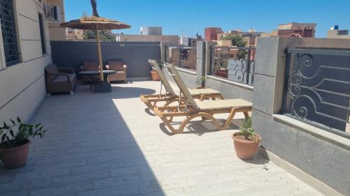 a patio with chairs and an umbrella on a balcony at Tibouda House Appartement De Luxe CAP R in Ras El Ma