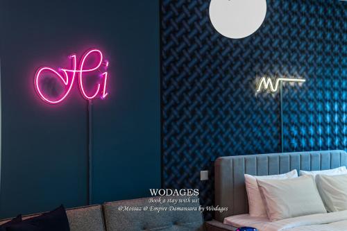 a bedroom with a bed and neon signs on the wall at Mossaz at Empire Damansara by Wodages in Kuala Selangor