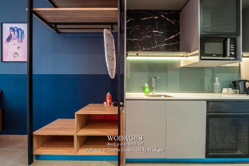 a kitchen with white cabinets and a wooden table at Mossaz at Empire Damansara by Wodages in Kuala Selangor