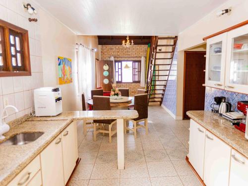 a kitchen with a table and a dining room at Casa com lareira e a 450 metros da praia QZ7460 in Penha