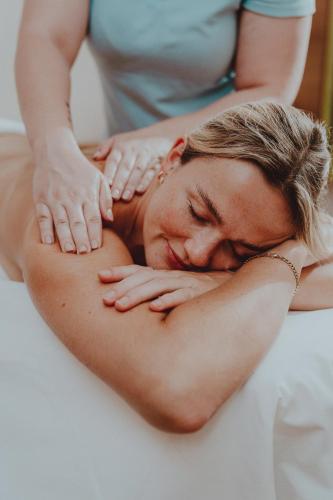 a woman is laying on a bed with her arms on her back at Appartements Amarella in Bad Hofgastein