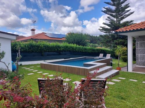 a swimming pool in a yard with chairs and a house at Casa da Marcolininha in Vieira do Minho